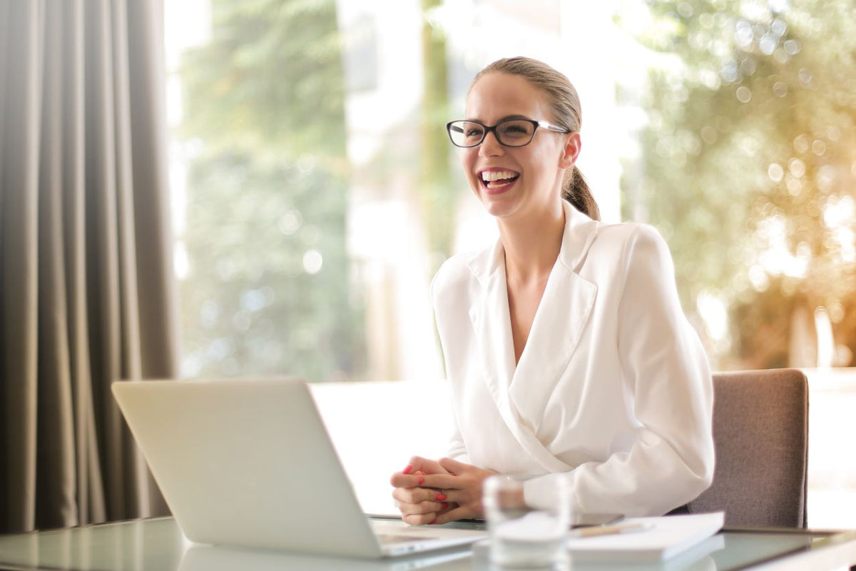 woman happy at desk after getting hired using a resume template